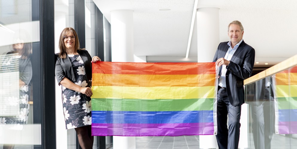 Foto von Nina Meyer und Dr. Brick. Sie halten einen Regenbogenflagge.