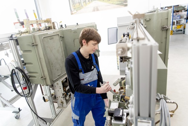 Ein Amprion-Azubi hält einen Schraubenschlüssel in der Hand. Er arbeitet am Umspannanlagen-Nachbau in Lotte.