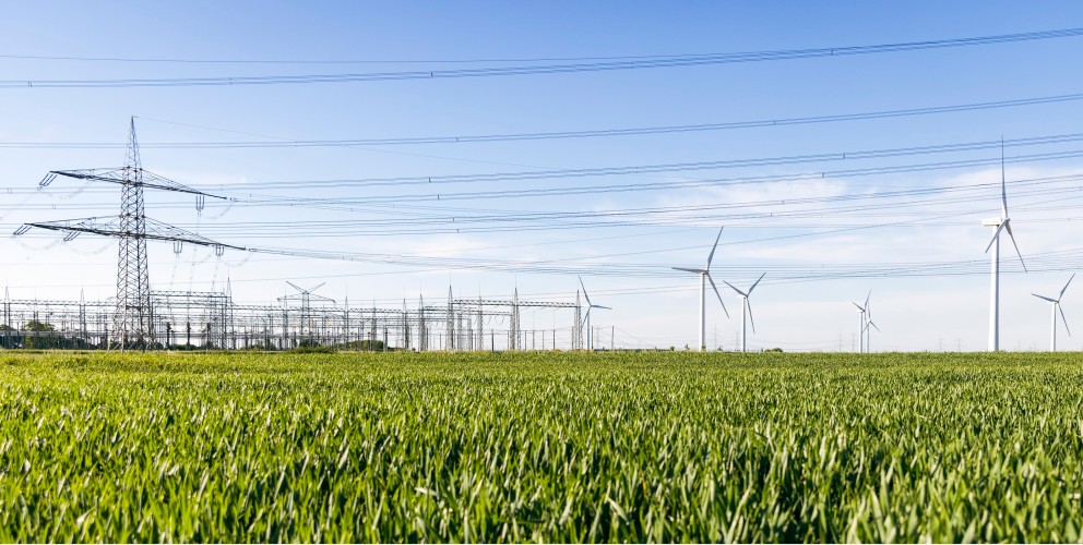 Freileitung, Höchstspannungsmast und Windräder an der Amprion-Umspannanlage Rommerskirchen, aufgenommen im Frühling