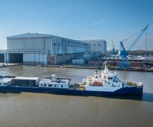 Beladenes Frachtschiff vor Meyer Werft im Wasser vor dem Werftgebäude.