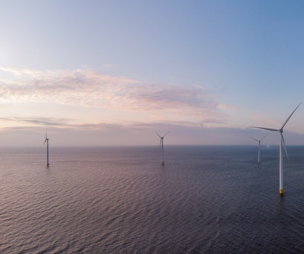 Das Bild zeigt einen Windradpark in der Nordsee. Die See schlägt leichte Wellen und der Himmel zeigt einige Wolken.